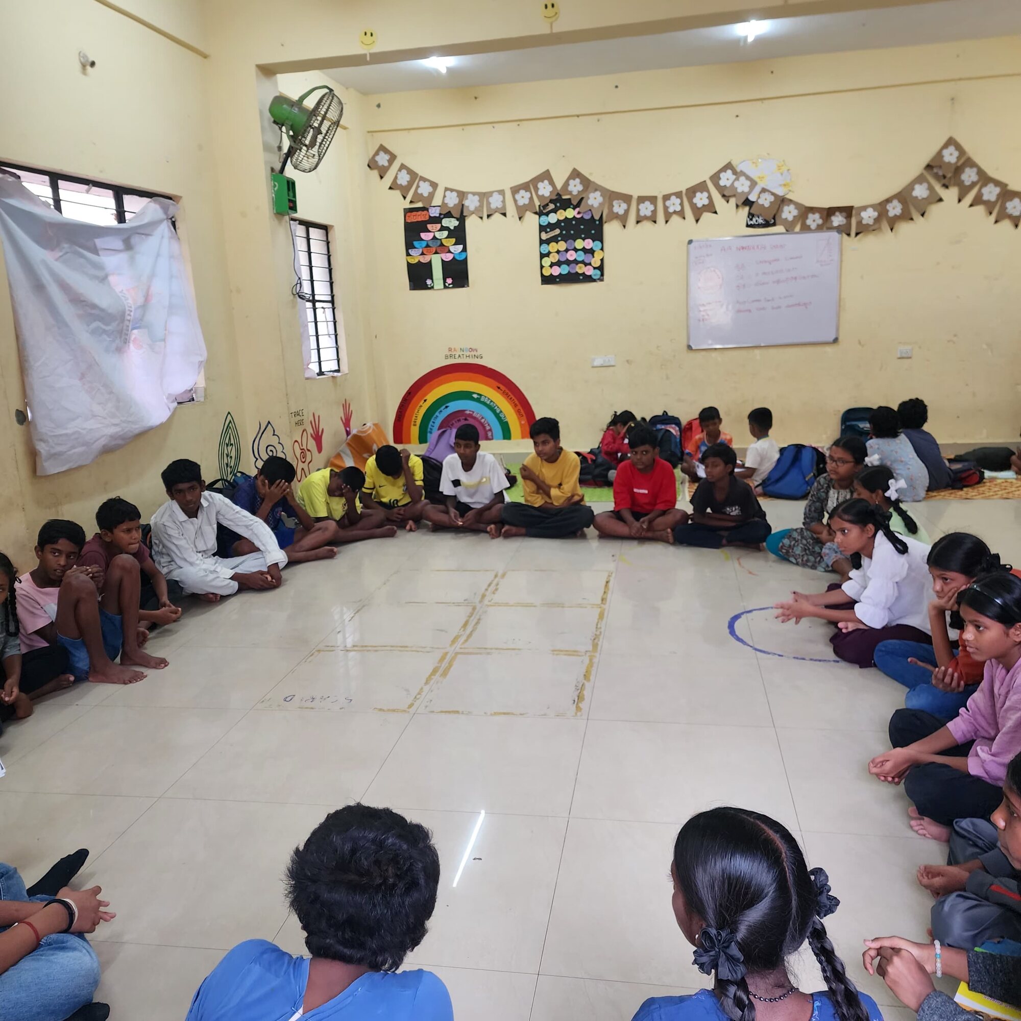Students seated in a circle around a floor activity