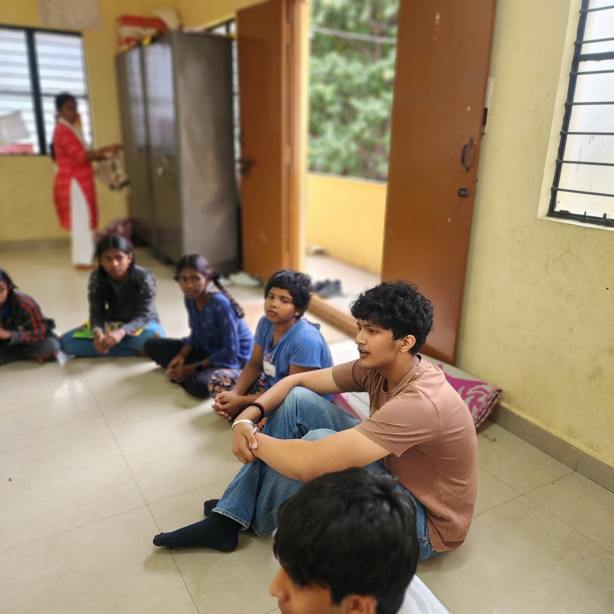 A WIEMO facilitator speaking with students seated in a circle